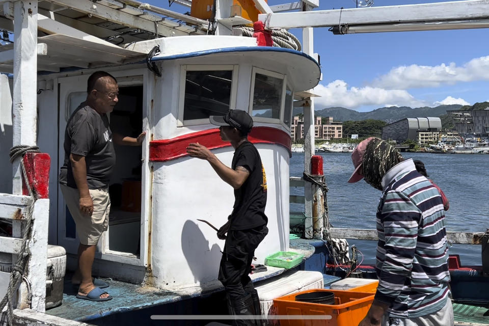 Fishing boat owner Chou Ting-tai, speaking to crew member while off-loading fishery products at Badouzi fishing port on Thursday in Keelung, Taiwan Thursday, Aug. 4, 2022. China says it conducted "precision missile strikes" in the Taiwan Strait on Thursday as part of military exercises that have raised tensions in the region to their highest level in decades. (AP Photo/Johnson Lai)