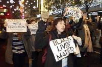 Protestors march with signs after a gathering to show solidarity with the family of black teenager Michael Brown outside the American Embassy in London November 26, 2014. REUTERS/Paul Hackett