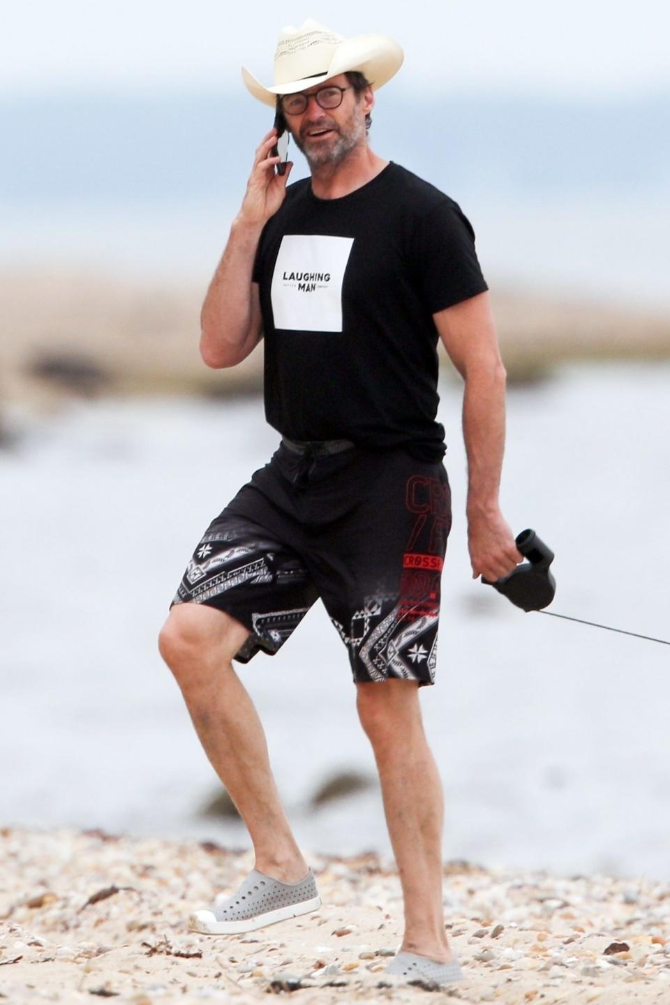 <p>Hugh Jackman chats on the phone while taking his pups for a walk on the beach in The Hamptons, New York, on Monday.</p>