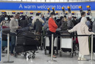 Passengers queue to Check in, at Heathrow Airport in London, Monday, Nov. 29, 2021. The new potentially more contagious omicron variant of the coronavirus popped up in more European countries on Saturday, just days after being identified in South Africa, leaving governments around the world scrambling to stop the spread. In Britain, Prime Minister Boris Johnson said mask-wearing in shops and on public transport will be required, starting Tuesday. (AP Photo/Frank Augstein)