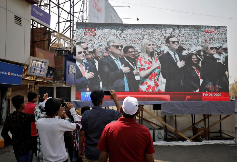 People watch a telecast showing White House senior advisors Jared Kushner and Ivanka Trump during the "Namaste Trump" event at Sardar Patel Gujarat Stadium, alongside a road in Ahmedabad