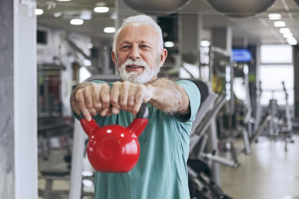 Senior man in gym working out using kettle bells