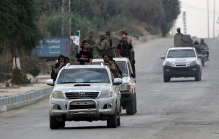 Turkey-backed Syrian rebel fighters ride on vehicles in the border town of Tal Abyad