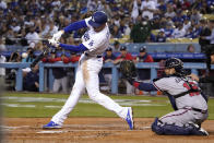 Los Angeles Dodgers' Freddie Freeman, left, hits a solo home run as Atlanta Braves catcher Travis d'Arnaud watches during the first inning of a baseball game Monday, April 18, 2022, in Los Angeles. (AP Photo/Mark J. Terrill)