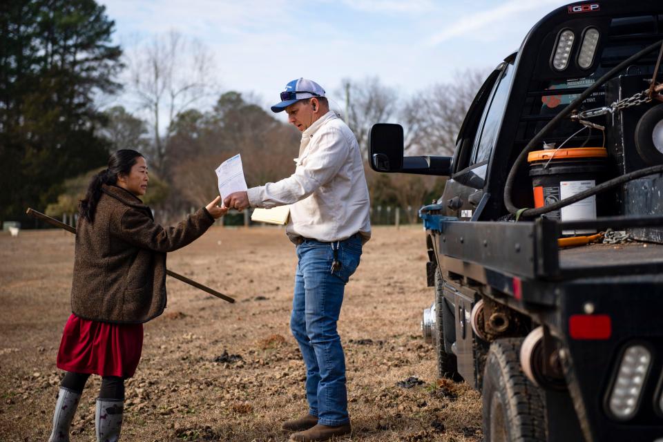 Allen Kellett, third-generation farmer and owner of Kellett Farms, gives an invoice to Shuli Hunt, a regular client for Keller, for a hay purchase to feed her animals on Saturday, Feb. 10, 2024.