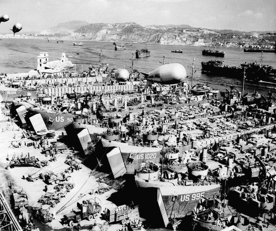 FILE - In this Aug.15, 1944 file photo, barrage balloons hover overhead as a line of WW II Landing Ships Tanks are loaded with vehicles and supplies in a southern Italian harbor. For Allied troops in western Europe, D-Day was just the beginning of a long and bloody push toward victory over the Nazis. Ten weeks after commemorating the 75th anniversary of the D-Day invasion in Normandy, France is paying tribute this week to Allied troops involved in another major, but often overlooked, military operation: landings on the Mediterranean coast. (AP Photo, File)