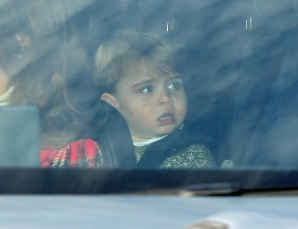 A photo of Prince Louis, 19 months, wearing a green jumper in the back seat of his mother's car en route to the Queen's Christmas lunch.