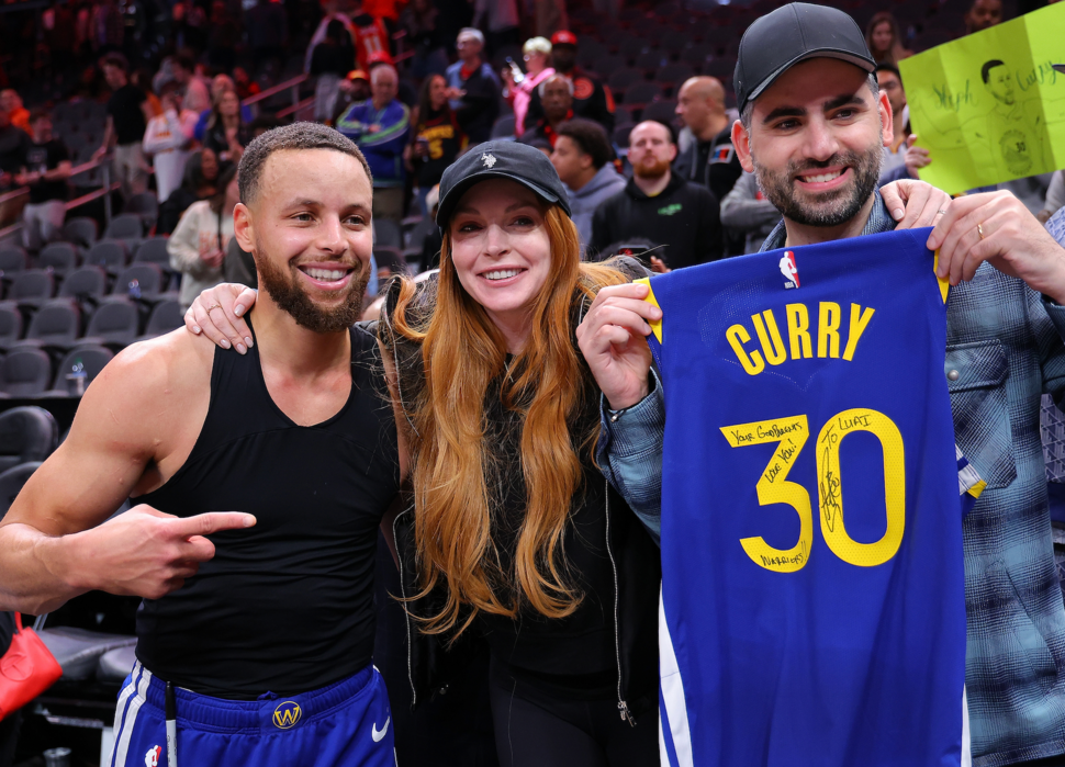 Stephen Curry #30 of the Golden State Warriors poses with actress Lindsay Lohan and her husband Bader Shammas after giving them his jersey in their 141-134 overtime loss to the Atlanta Hawks at State Farm Arena on February 03, 2024 in Atlanta, Georgia.