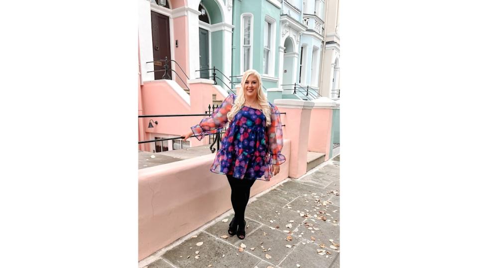 woman in front of pink and green houses