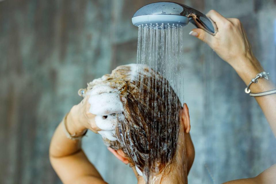 <p>skynesher/Getty</p> Stock image of a woman washing her hair in a bathroom