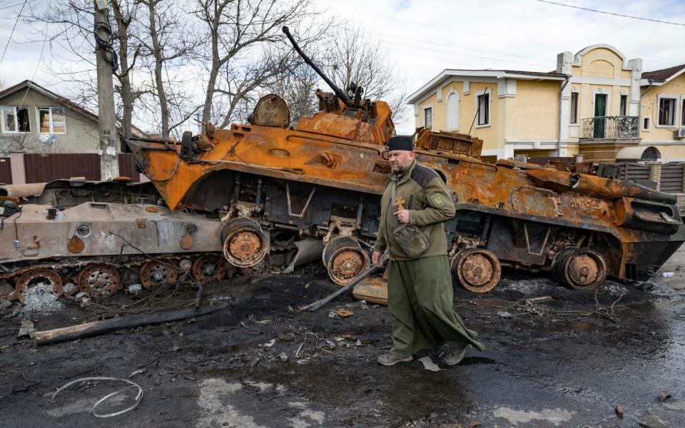 A citizen of Bucha walks past a destroyed Russian tank - Paul Grover