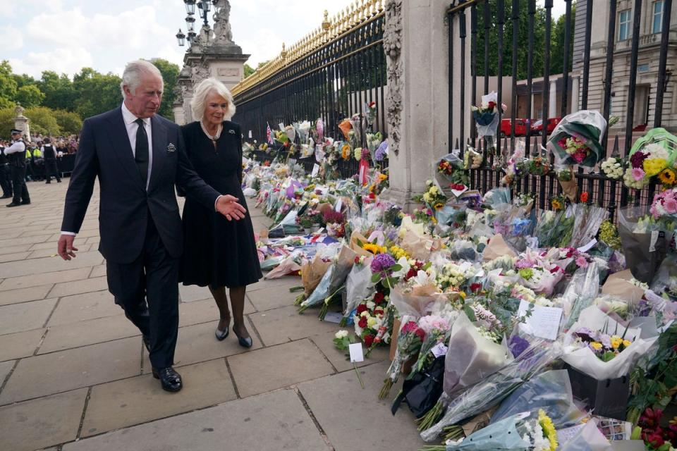 La pareja real observa las ofrendas florales fuera del Palacio de Buckingham el viernes (PA)