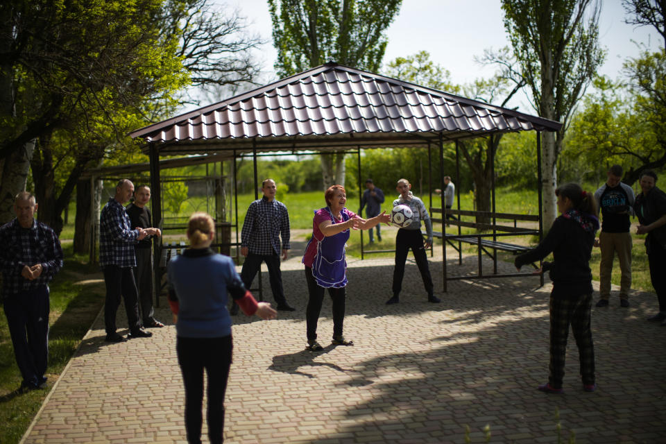 A worker, center, tosses a ball with residents at a facility for people with mental and physical disabilities, in the village of Tavriiske, Ukraine, Wednesday, May 11, 2022. The staff is faced with the dilemma of evacuating the facility, and how to do it with minimum disruption to the residents, some of whom have very severe disabilities and others for whom changes in environment can be disorientating and highly stressful. (AP Photo/Francisco Seco)