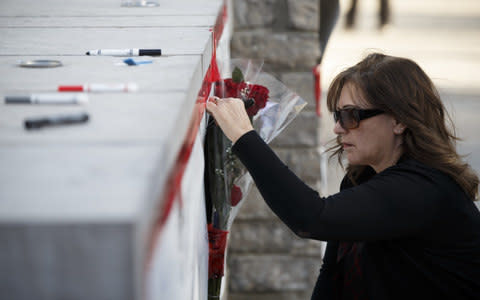 A woman signs a memorial card for the victims near the scene - Credit: Cole Burston 