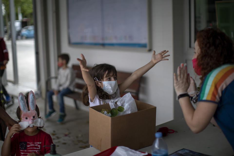 A primary school student gestures for a hug from a distance to her teacher, as she collects her personal belongings, as the school year ends, in a school in Barcelona, Spain, Tuesday, June 16, 2020. (AP Photo/Emilio Morenatti)