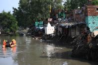 National Disaster Response Force personnel inspect on a dinghy the area where some shanty houses collapsed into a canal due to heavy rains in New Delhi on July 19, 2020. (Photo by Sajjad HUSSAIN / AFP) (Photo by SAJJAD HUSSAIN/AFP via Getty Images)