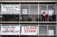 A resident untangles a Canadian flag in order to tape it back up to a window on a balcony at Laurier Manor, a long-term care facility experiencing an outbreak of COVID-19, Sunday, April 26, 2020, in Ottawa, Ontario. (Justin Tang/The Canadian Press via AP)