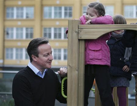 A child looks at Britain's Prime Minister David Cameron during his visit to the Coin Street nursery in London March 18, 2014. REUTERS/Peter Macdiarmid/pool