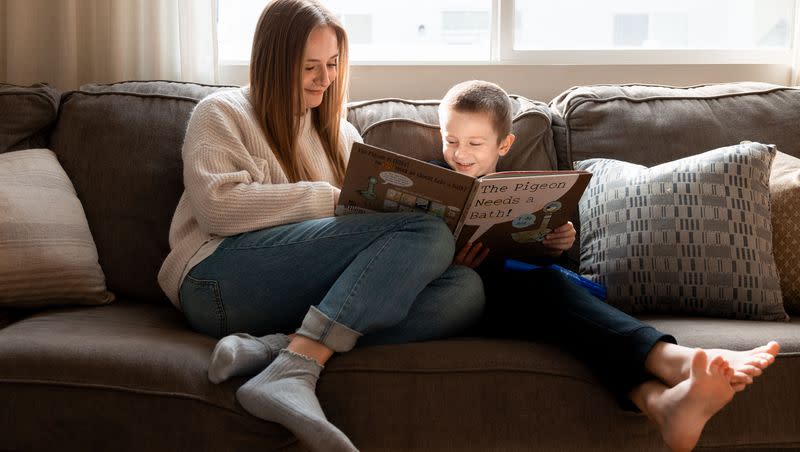 Lauren Hess and one of her children read a book at their home in Syracuse on Saturday, Jan. 6, 2024. Hess has worked to make her home cozy and to appreciate unique aspects of the season in an effort to boost her mood during the winter.