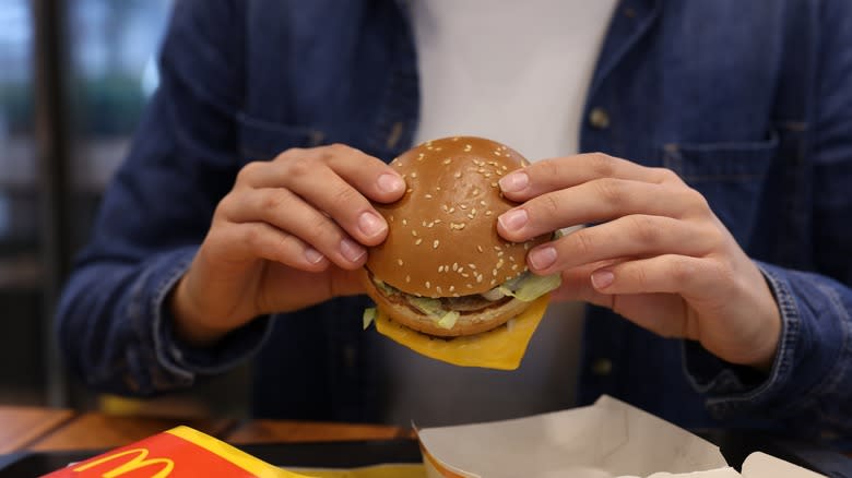 hands holding a mcdonald's hamburger