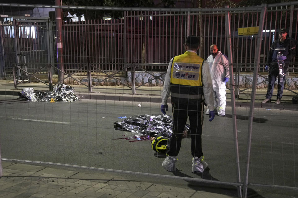 Members of Zaka Rescue and Recovery team check victims of a shooting attack near a synagogue in Jerusalem, Friday, Jan. 27, 2023. A Palestinian gunman opened fire outside an east Jerusalem synagogue Friday night, killing five people and wounding five others in one of the deadliest attacks on Israelis in years, medical officials said. The attack was halted when the gunman was shot by police. (AP Photo/Mahmoud Illean)