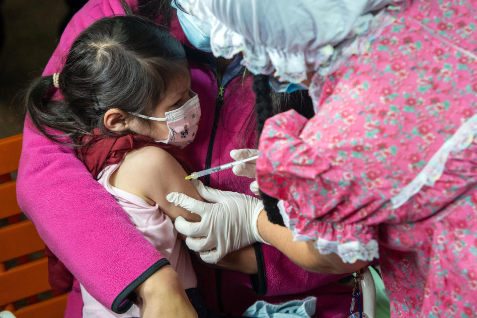 A girl is inoculated with the Sinovac vaccine againsgt COVID-19 by a disguised worker of the Public Health Ministry at the Maria Montessori Initial Education Center, in Quito, on February 15, 2022