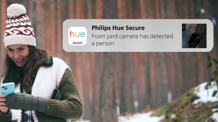 A woman receiving an alert from a Philips Hue Secure camera