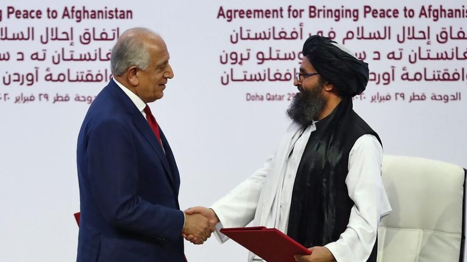 Zalmay Khalilzad y el cofundador del Talibán, Mullah Abdul Ghani Baradar, se dan la mano.