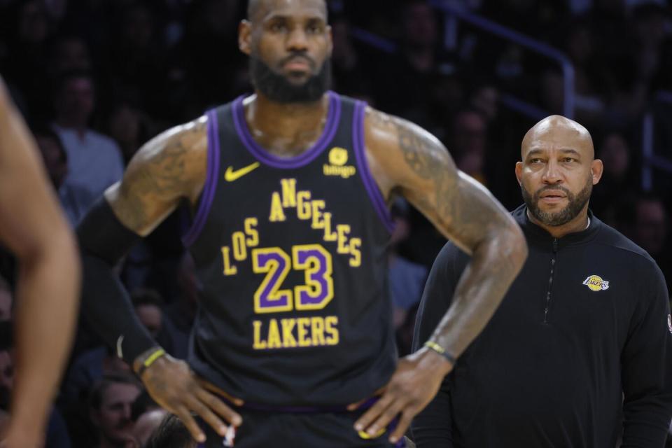 Darvin Ham looks on from the bench and he stands behind LeBron James.