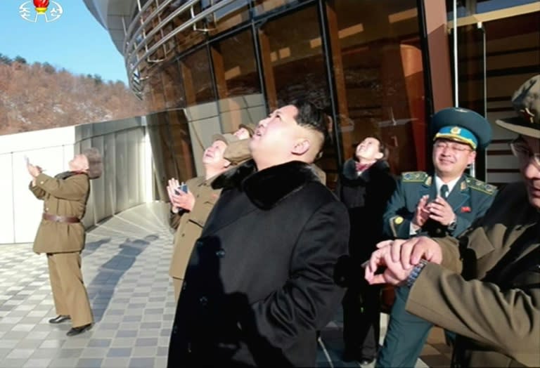 Picture taken from North Korean TV and released by South Korean news agency Yonhap shows North Korean leader Kim Jong-Un (C) looking at the rocket launch