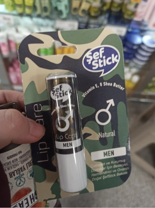 Hand holding a camouflage package of 'Sef Stick Lip Care for Men' with a lip balm tube visible