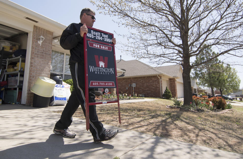 Scott Teel, a high school history teacher, carries a 'for sale' sign, as part of his second job as a real estate agent, in Moore, Oklahoma. (Credit: J Pat Carter/ AFP, via Getty Images)    