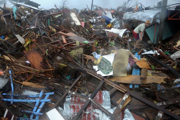 A man walks past a dead body covered with cloth among debris of destroyed houses in Tacloban, eastern island of Leyte on November 10, 2013