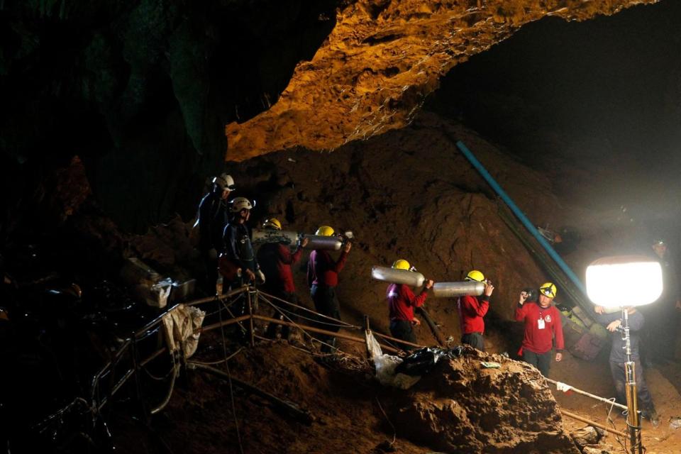 Thai officials carry oxygen tanks through a cave complex during the rescue operation (EPA)