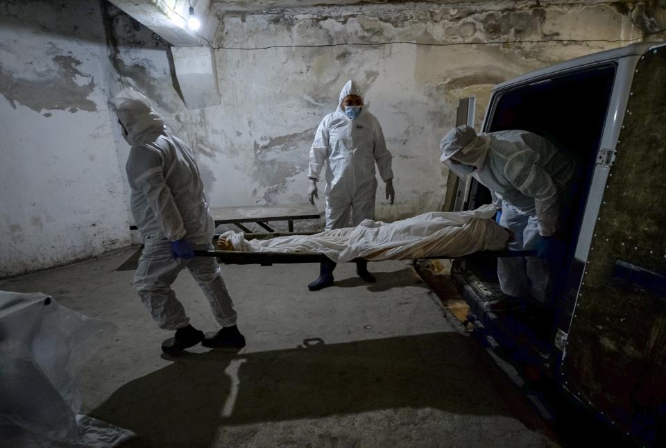 Pathologists in protective suits transport the body of a person who died of the coronavirus at a hospital's morgue in Bishkek, Kyrgyzstan, Wednesday, July 22, 2020. Coronavirus cases surged in Kyrgyzstan after authorities lifted a tight lockdown in May, overwhelming the health care system. But now thousands of volunteers are helping medical workers in busy hospitals, using cars into makeshift ambulances and finding protective gear, drugs, supplies and equipment. (AP Photo/Vladimir Voronin)