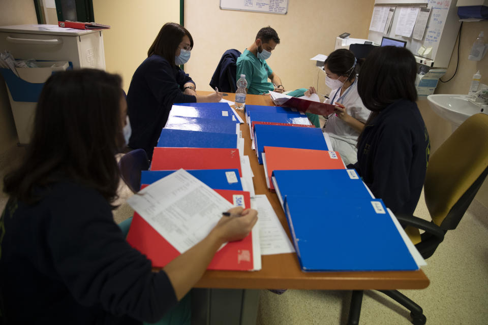 Dr. Elisabetta Teti, second from left, takes notes during the morning briefing at the infectious disease department of the Tor Vergata Polyclinic Hospital, in Rome, Saturday, Nov. 7, 2020. On Saturday Teti was handling two sub-intensive care Covid Units with 28 patients, 18 of them in breathing helmets. She was also supervising the COVID-19 cases flowing non-stop into the emergency room, a total of roughly 70 people with the deadly coronavirus. (AP Photo/Alessandra Tarantino)