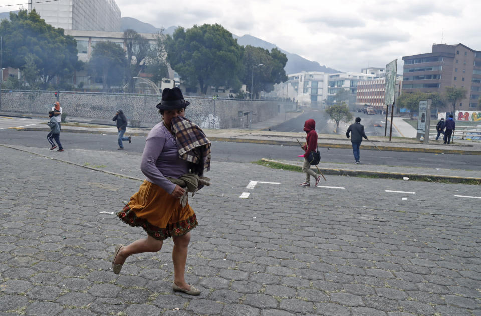 An indigenous anti-government protester runs from tear gas fired by police during clashes near the National Assembly in Quito, Ecuador, Tuesday, Oct. 8, 2019. Anti-government protests, which began when President Lenín Moreno’s decision to cut subsidies led to a sharp increase in fuel prices, has persisted for days, and clashes led the president to move his besieged administration out of Quito. (AP Photo/Dolores Ochoa)