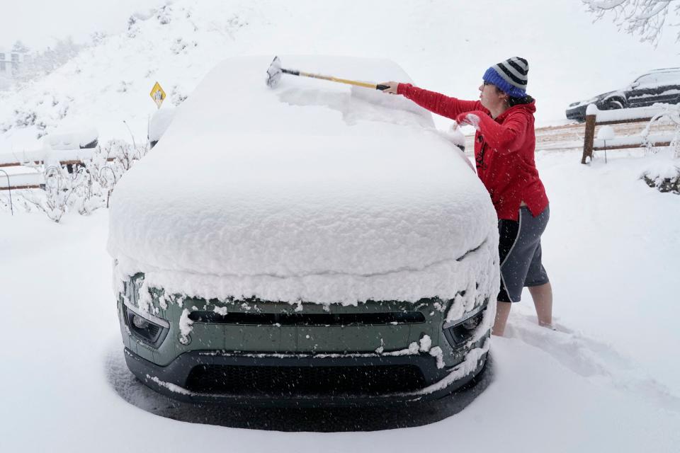 A person clears their car of snow to go to work, in Provo, Utah, on Feb. 22, 2023.