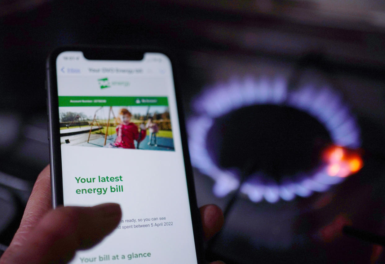 A general view of a household energy bill displayed on a mobile phone held next to a gas hob. Families across Great Britain will find out on Friday how tough energy bills will be this winter but they may have to wait to discover what the Government will do to help Picture date: Thursday August 25, 2022. (Photo by Yui Mok/PA Images via Getty Images)