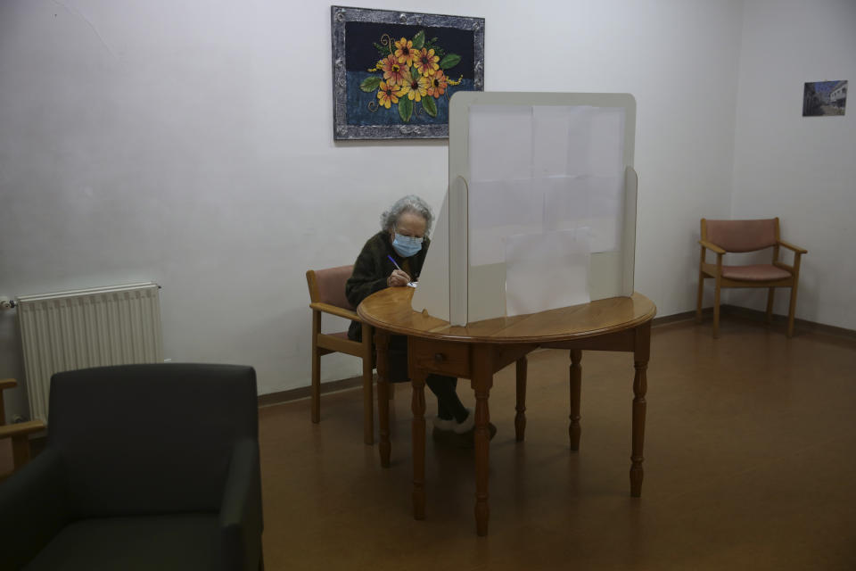 Rosa Gordo, 89, marks her presidential election ballot behind a makeshift voting booth at the elderly care home where she resides in Montijo, south of Lisbon, Tuesday, Jan. 19, 2021. For 48 hours from Tuesday, local council crews are collecting the votes from people in home quarantine and from residents of elderly care homes ahead of Sunday's presidential election. (AP Photo/Armando Franca)