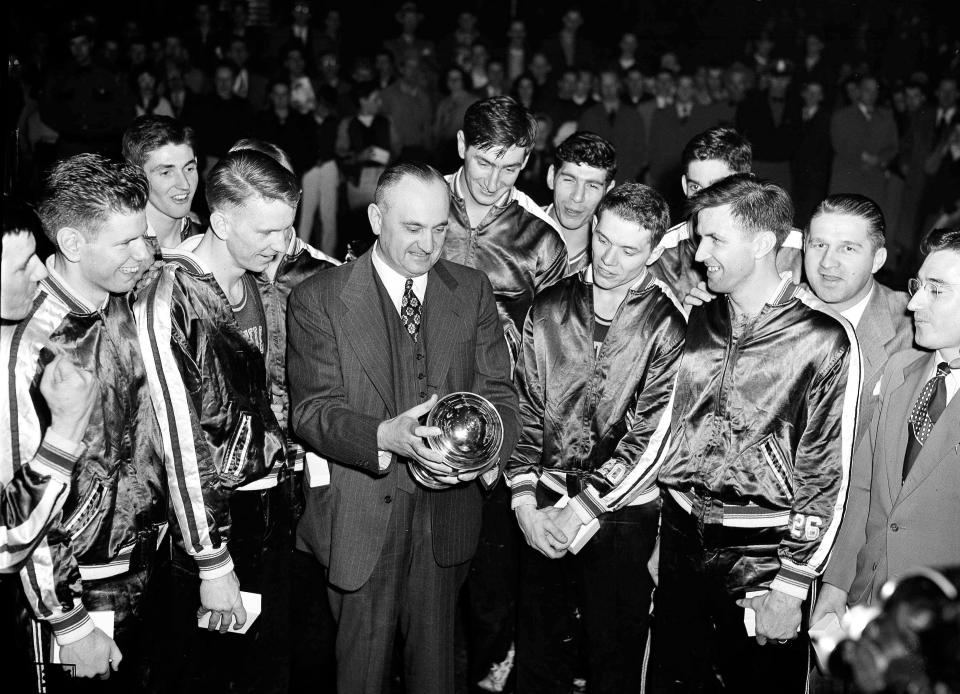 FILE - University of Kentucky coach Adolph Rupp and his team admire the NCAA basketball title cup which they won at Seattle, March 26, 1949, by defeating Oklahoma A&M, 46-36. Front row, left to right: Jim Line, Walter Hirsch, Coach Rupp; Ralph Beard, and Clifford Barker. Star center Alex Groza looks over Rupp's shoulder. Others are unidentified. The first AP Top 25 men's college basketball poll was published on Jan. 17, 1949. Saint Louis was installed at No. 1 ahead of mighty Kentucky. (AP Photo/Paul Wagner, File)