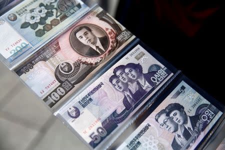 A souvenir vendor displays what he said was North Korean money at the bank of the Yalu river in China's Dandong, Liaoning province, opposite North Korea, September 11, 2016. REUTERS/Thomas Peter