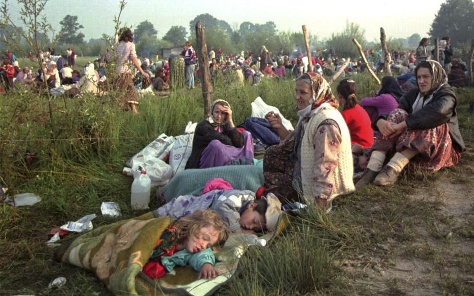 FILE - In this Friday, July 14, 1995, file picture, refugees from Srebrenica who had spent the night in the open air, gather outside the U.N. base at Tuzla airport. Survivors of the genocide in the eastern Bosnian town of Srebrenica, mainly women, will on Saturday July 11, 2020, commemorate the 25th anniversary of the slaughter of their fathers and brothers, husbands and sons. (AP Photo/Darko Bandic, File)