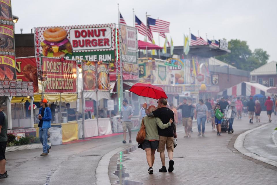 Ken and Jane Kuzma of Lancaster search for food as drizzle falls during the opening day of the Ohio State Fair. This year is the first full edition of the popular event since 2019.