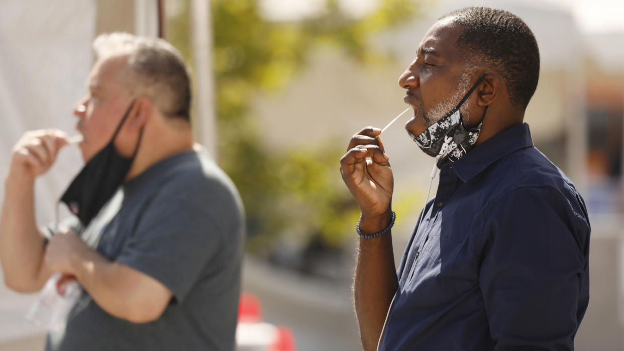 Charles Davis, 49, right, self administers the oral swab test during Coronavirus Covid-19 testing in LA County at the Charles R. Drew University of Medicine and Science in South Los Angeles on July 8, 2020. (Al Seib / Los Angeles Times via Getty Images)