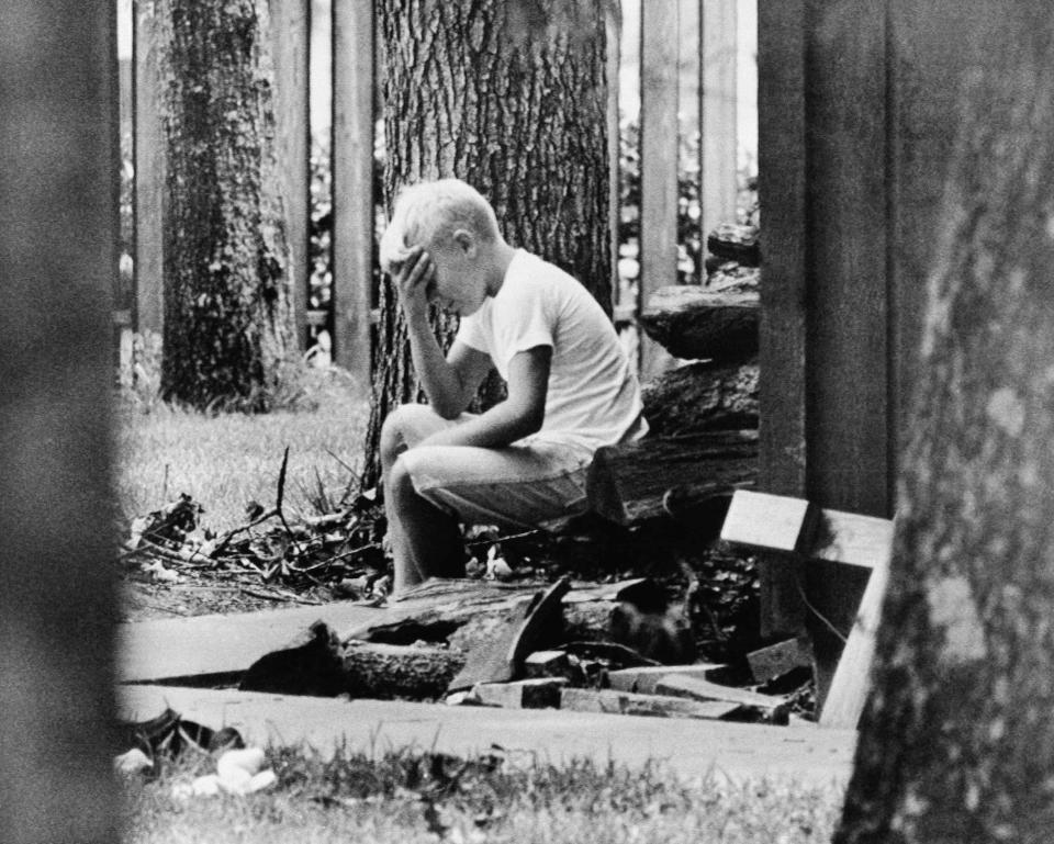 FILE - In this July 20, 1969 file photo, Andy Aldrin, 10, sits on a pile of cordwood in the backyard of his home in Houston while other members of his family listen to the reports of the progress of the Apollo II lunar module carrying his father, Col. Buzz Aldrin and fellow astronaut Neil Armstrong to a landing on the moon. (AP Photo)