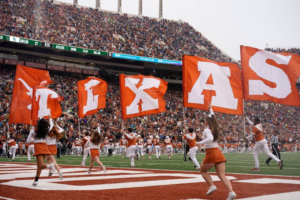 Members of the Texas Longhorns spirit squad carry flags across the field after a touchdown against Baylor at Royal-Memorial Stadium this past season. Texas athletic director Chris Del Conte said he intends to replace DKR's field turf with natural grass but must wait until the football team has a new indoor practice facility.