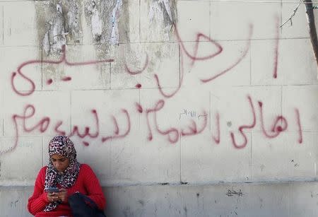 A woman talks on her mobile phone in front of a wall with graffiti asking Egyptians to participate in demonstrations against the Egyptian regime and against economic conditions following the rise of prices around the country, in Cairo, Egypt November 9, 2016. The words read, "Leave Sisi, Egypt not for sale". REUTERS/Amr Abdallah Dalsh