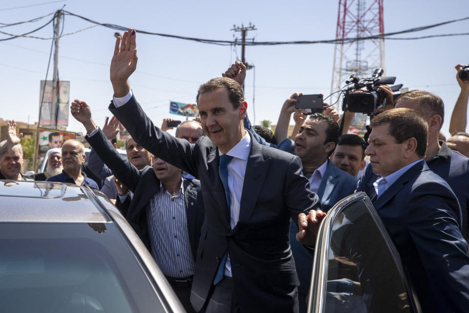 FILE - Syrian President Bashar Assad waves for his supporters at a polling station during the Presidential elections in the town of Douma, in the eastern Ghouta region, near the Syrian capital Damascus, Syria, Wednesday, May 26, 2021. French judicial authorities on Wednesday issued international arrest warrants for Syrian President Bashar Assad, his brother Maher, and two army generals alleging their involvement in war crimes and crimes against humanity, including in chemical attacks in 2013 on rebel-held Damascus suburbs, lawyers for Syrian victims said. (AP Photo/Hassan Ammar, File)