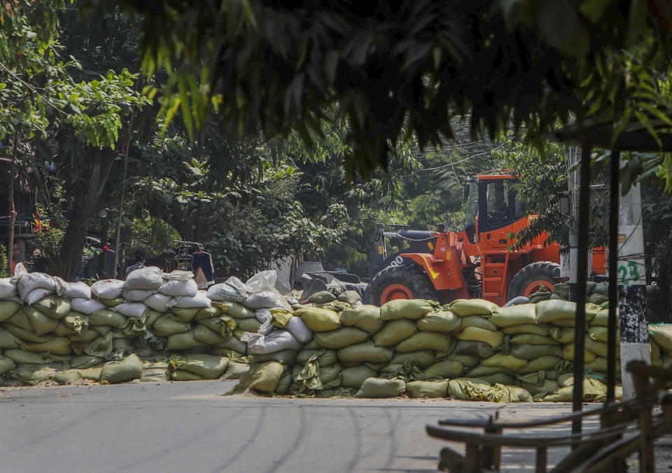 A man watches as soldiers use a bulldozer to remove sandbag barricades put in place by anti-coup protesters to protect them from security forces in Mandalay, Myanmar, Thursday, March 18, 2021. (AP Photo)